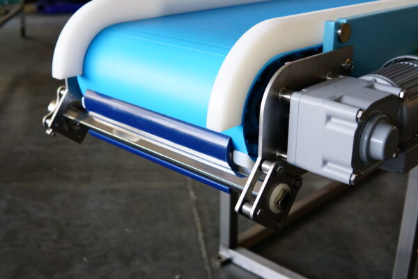 A close up of a scraper blade on a blue food conveyor belt