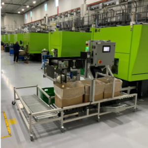 A box filling conveyor with a right angle roller conveyor attached in a factory with bright green machinery