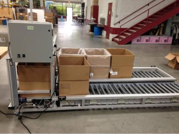 A Side by Side Box Filling Conveyor very low to the ground in a manufacturing facility