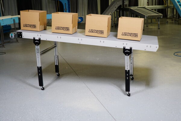 A Dynapro low profile incline conveyor with adjustable height legs and four boxes on top