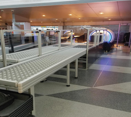 DynaRoller powered roller conveyors in an airport security terminal being used to convey baggage and totes