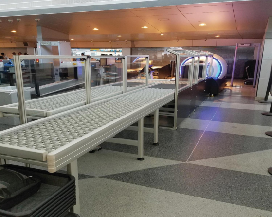 DynaRoller powered roller conveyors in an airport security terminal being used to convey baggage and totes