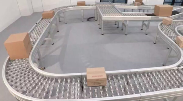 A packaging conveyor with boxes on top, powered rollers, many radius turns, and transfer sections