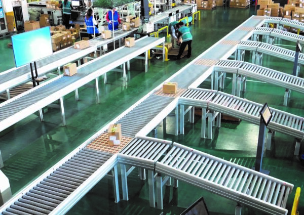 Boxes being conveyed and transferred on a roller conveyor in a sortation warehouse