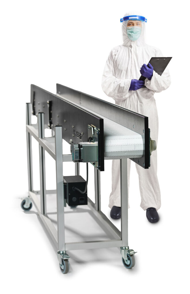 An employee in protective gear standing with a clipboard next to a Hybrid clean room conveyor