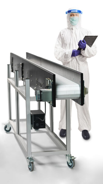 A pharmaceutical conveyor with clean room ready accessories and a man in full ppe gear standing next to it