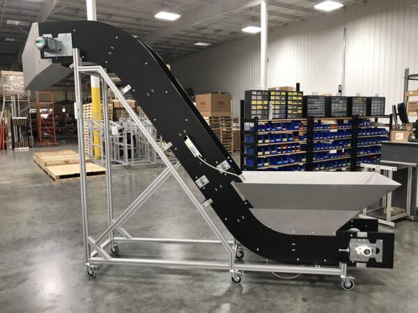 A metal detection conveyor with a hopper and an exist chute after just being assembled in a warehouse