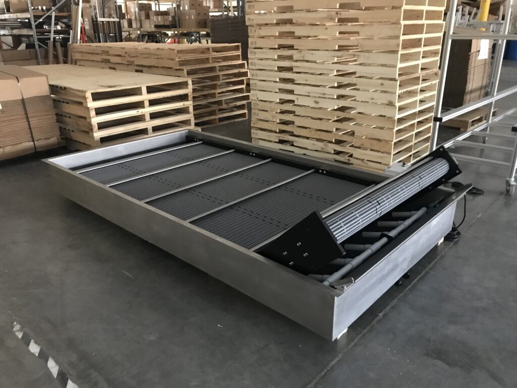 A Hybrid water bath conveyor with pallets in the background
