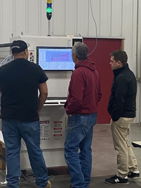 Muskegon area teachers looking at the software panel of a machine in a conveyor manufacturing facility