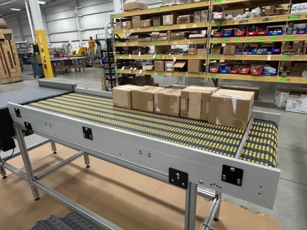 Accumulation low presser insert rollers Dynamic Conveyor side view of accumulating conveyor belt with boxes on it