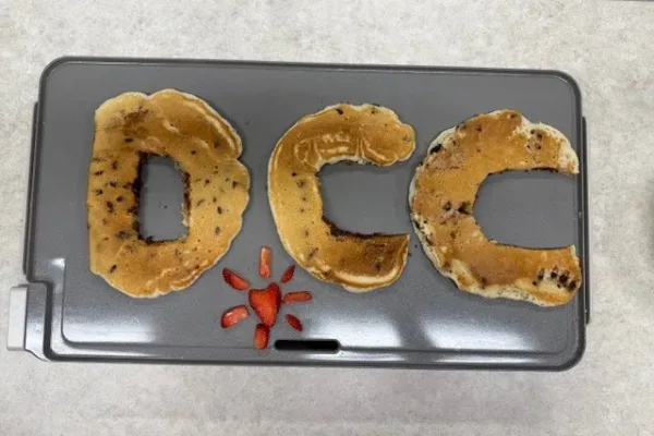 DCC-Branded-Pancakes pancakes shaped in the letters DCC with strawberries arranged like the logo icon