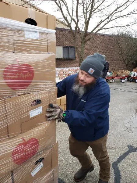 feeding-america-pallet-food-2 volunteer moving boxes of apples at West Michigan Feeding America event in Muskegon