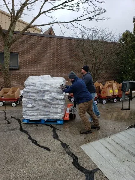 feeding-america-volunteers-2026-3 workers moving heavy pallet of donated food