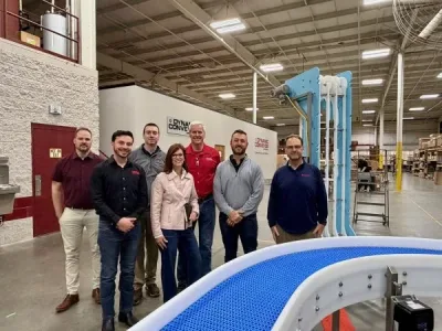 group of Intralox and Dynamic Conveyor staff in front of DynaClean conveyor belt