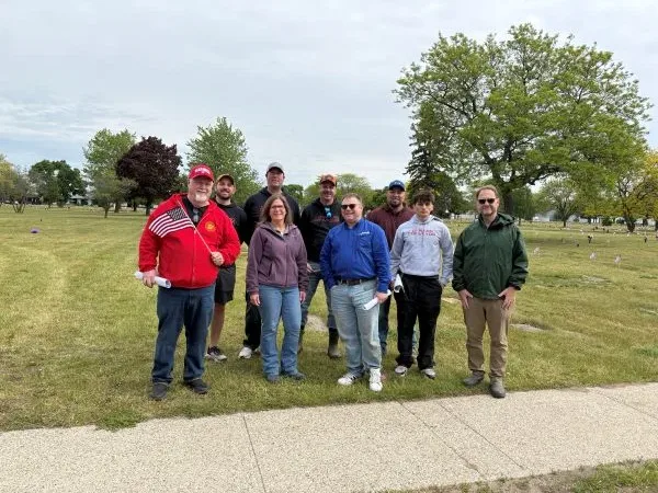2026-memorial-day-muskegon-1 Dynamic Conveyor staff members standing for group photo at Sunrise Memorial Gardens after placing flags to honor veterans