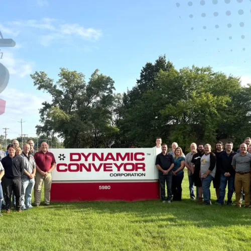 Dynamic Conveyor staff standing by company sign outside at Norton Shores Michigan location