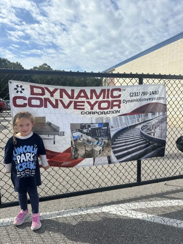 2026-walkathon-Student-Banner student standing by Dynamic Conveyor company banner
